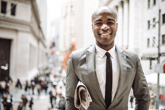 man in suit outside with newspaper under arm
