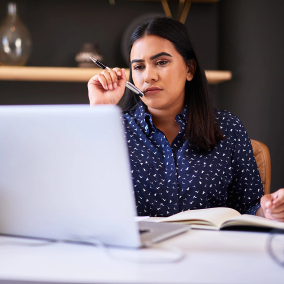 Woman reading on laptop and taking notes