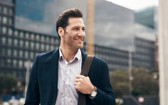 A professional carrying a shoulder bag walks past modern office buildings in an urban setting. The image suggests a working environment linked to finance or investment management, reflecting the daily context of institutional investors and professionals operating in global private markets