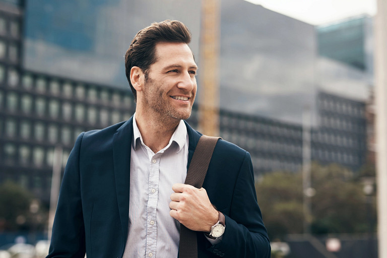 A professional carrying a shoulder bag walks past modern office buildings in an urban setting. The image suggests a working environment linked to finance or investment management, reflecting the daily context of institutional investors and professionals operating in global private markets